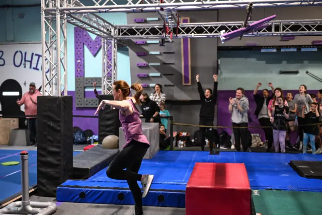 An athlete with her arms raised after her run as the crowd cheers