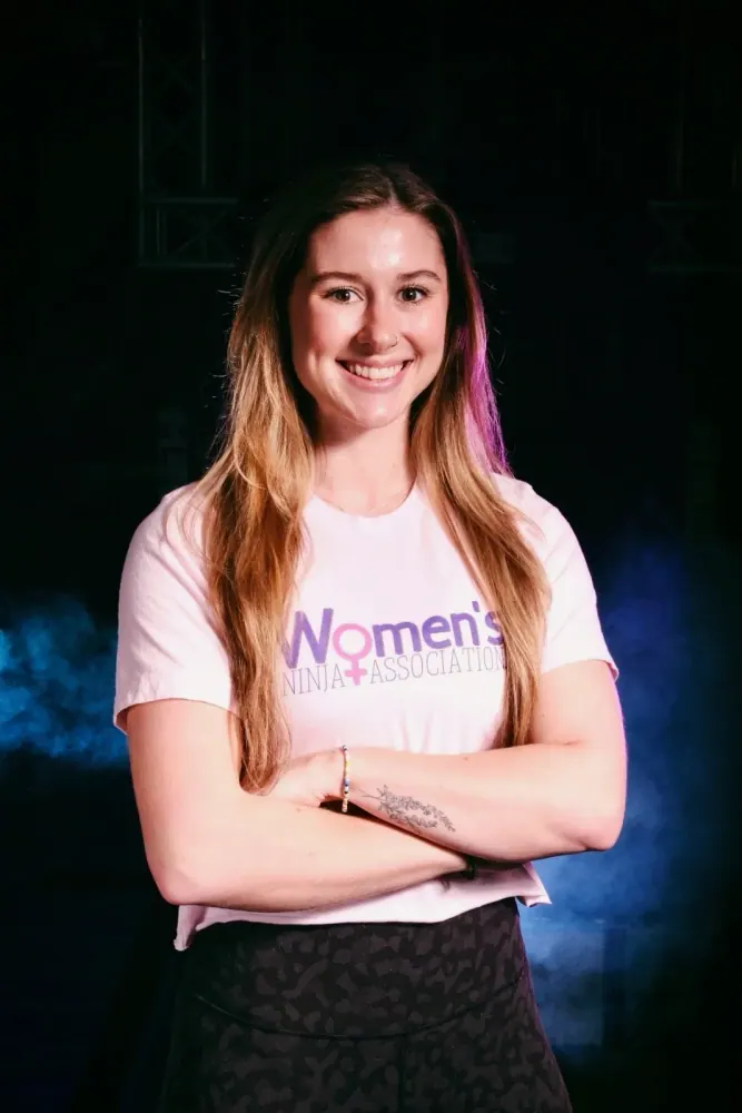 Jennifer Sanders in a Women's Ninja Association shirt, arms crossed and smiling