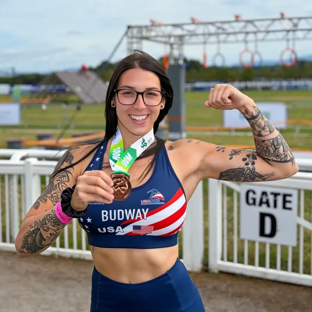 Megan Budway in her Team USA kit, holding up her bronze medal from the 100m World Championships